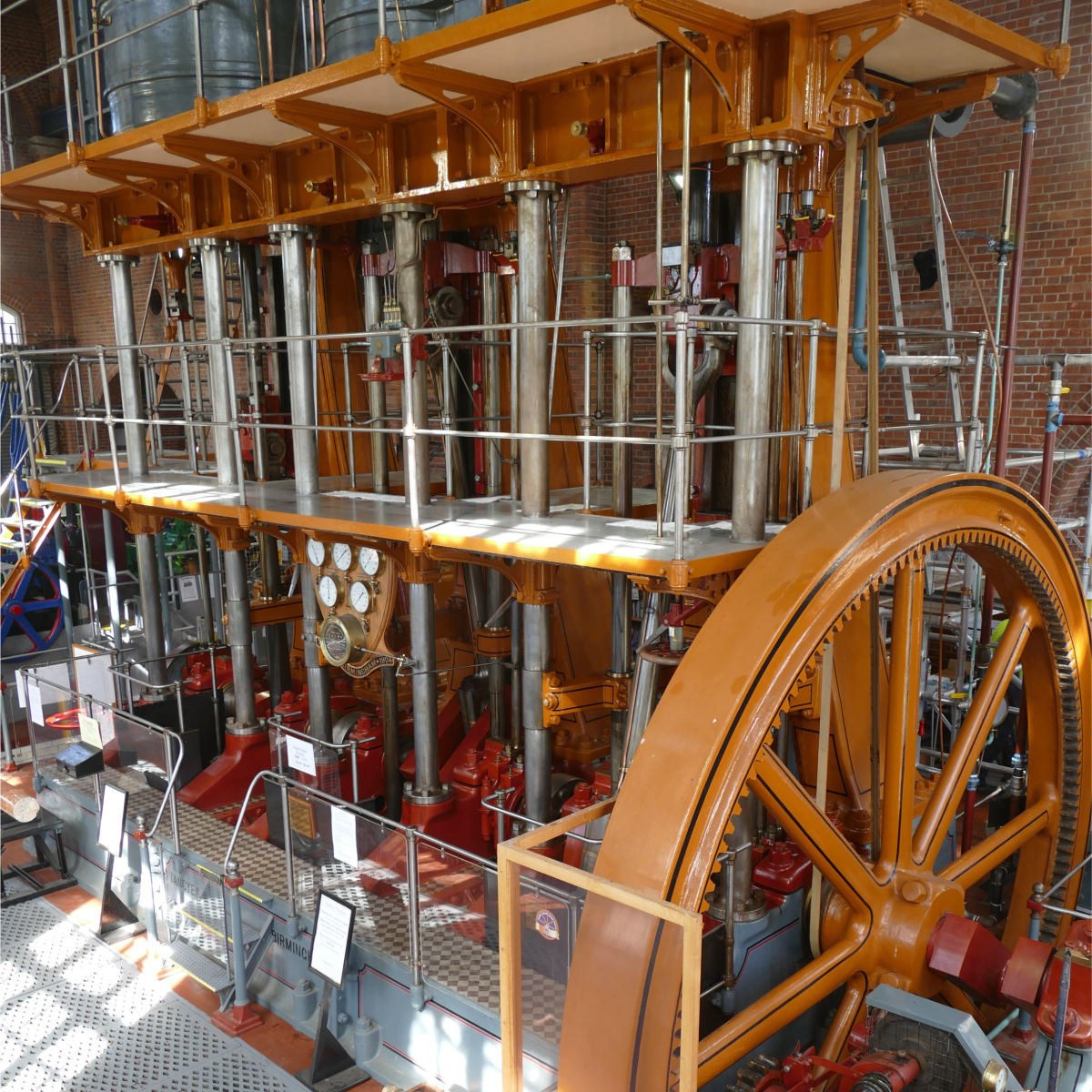 Interior of the Brede Steam Giants, showing a vast historic steam engine with large flywheel, columns, and gauges.